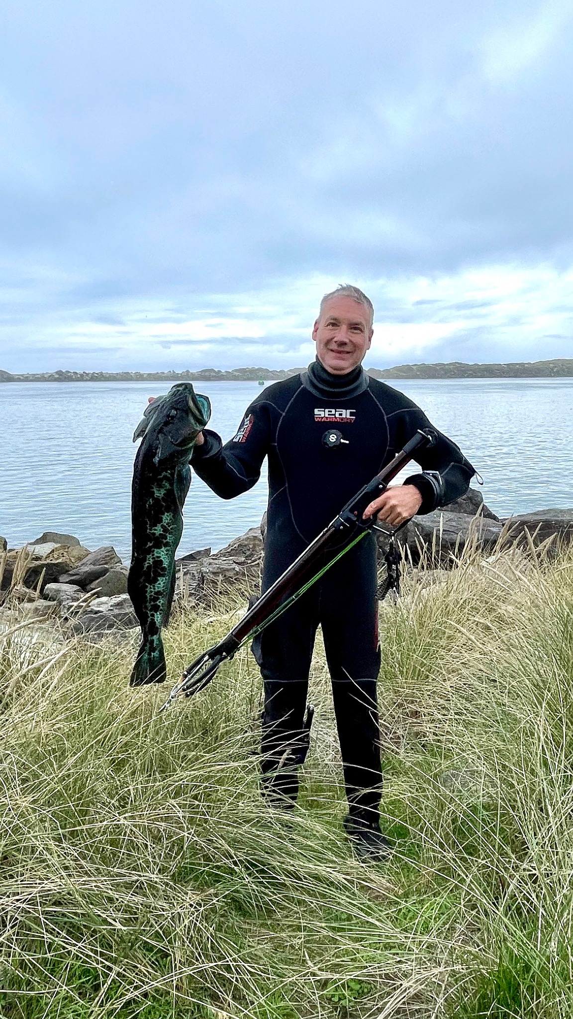Daniel Bray holding a lingcod and speargun after an Oregon shore dive